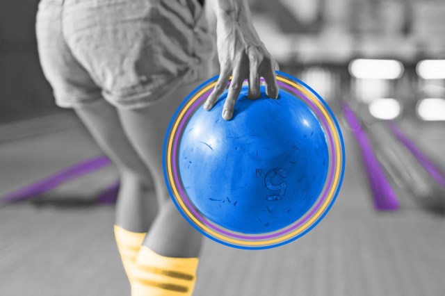 Person approaching a bowling lane holding a bowling ball