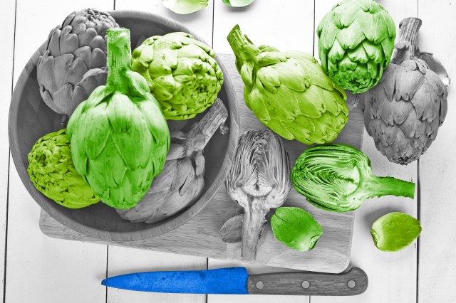 Kitchen knife lying next to overflowing bowl of artichokes