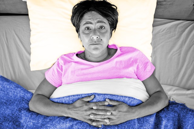 Woman lying in bed looking up at ceiling in distress